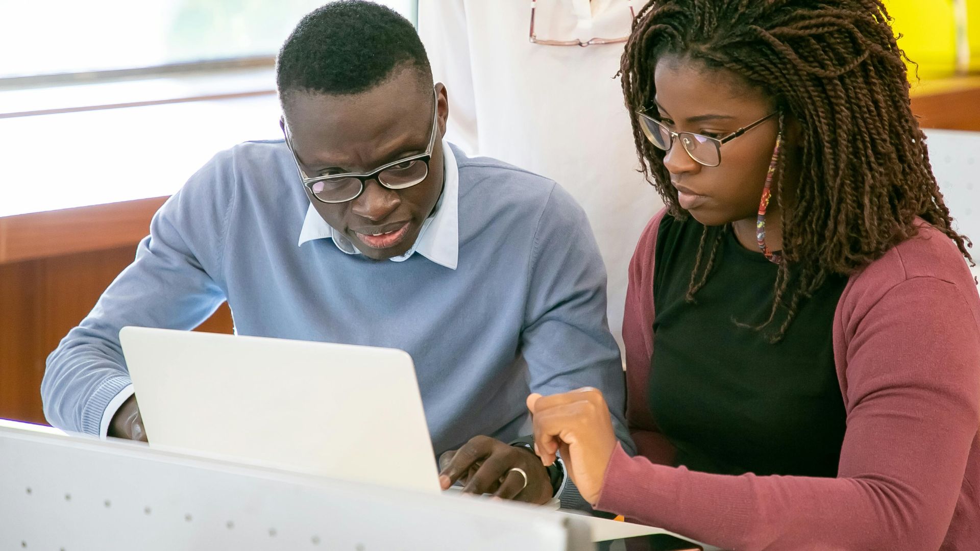 Two educators working at a laptop